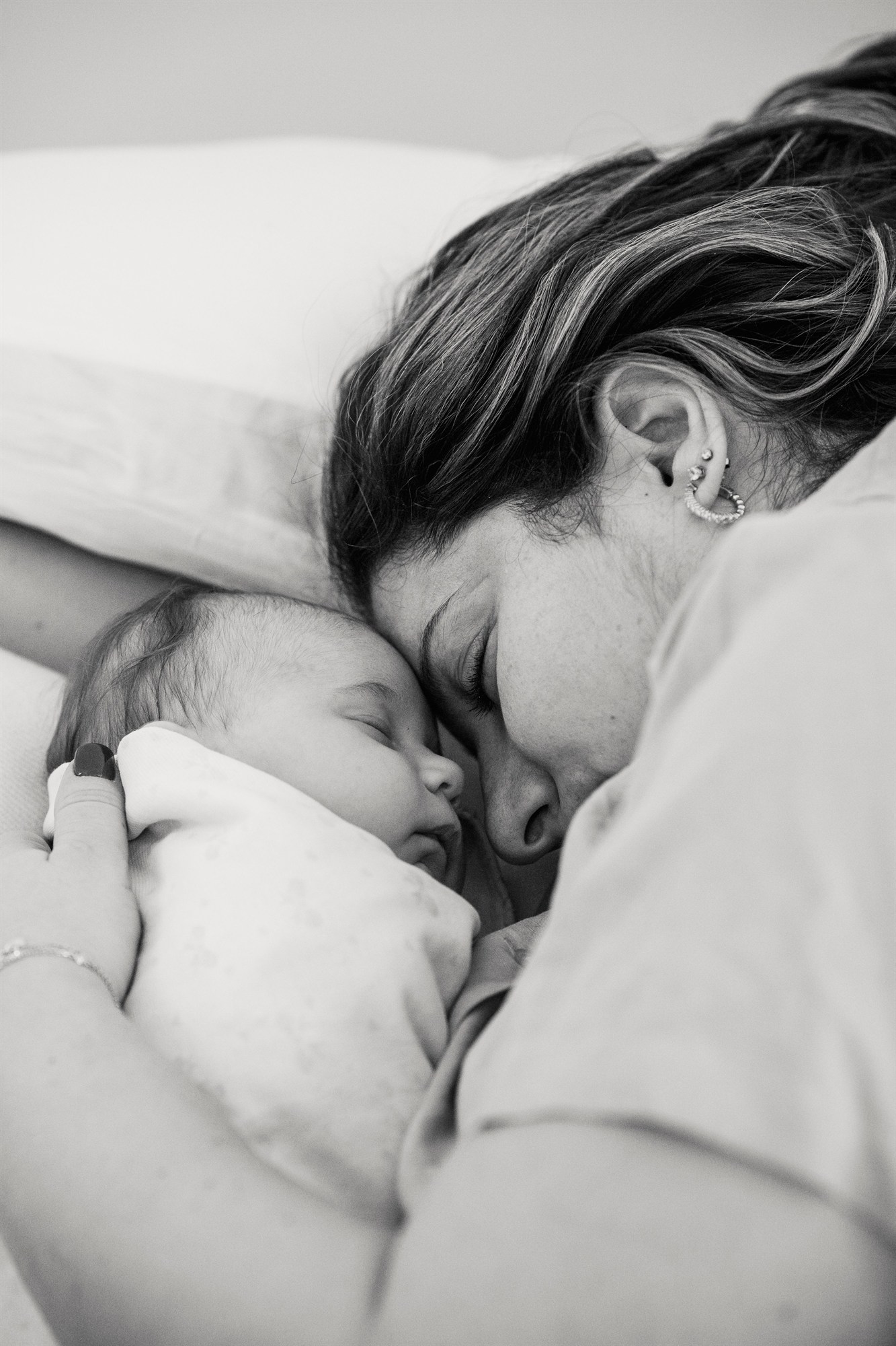 A new mother rests peacefully with her sleeping newborn at DeRAMA Singapore's postpartum care suite